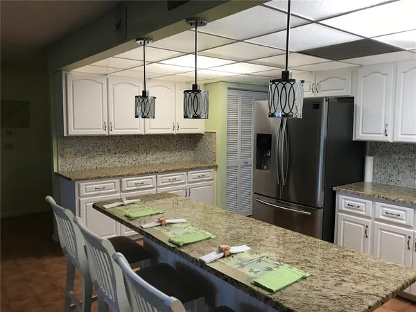 a kitchen with stainless steel appliances granite countertop a sink a stove a refrigerator a washer dryer and white cabinets
