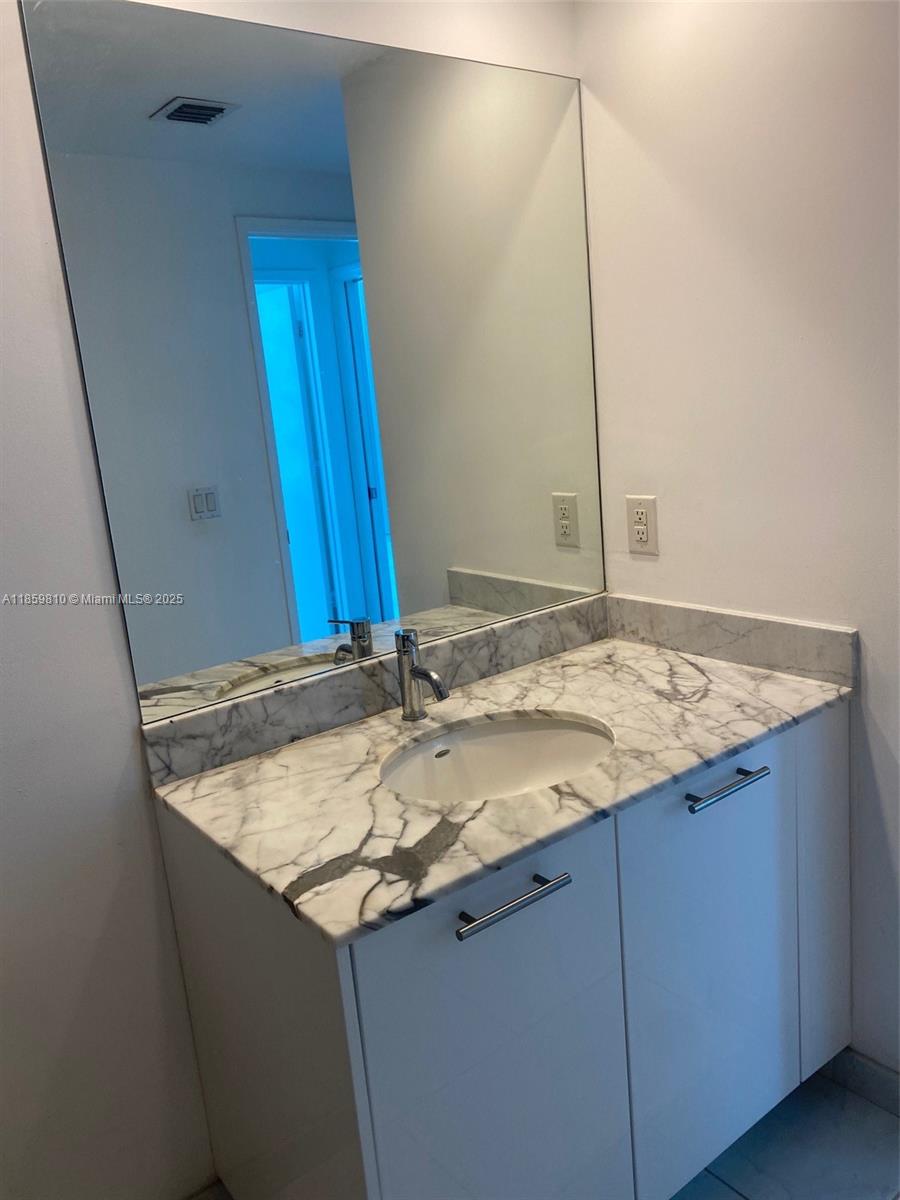 951 Brickell Avenue, Unit 3609 Miami, FL 33131 - Photo 15 of 25 a bathroom with a granite countertop sink and a mirror