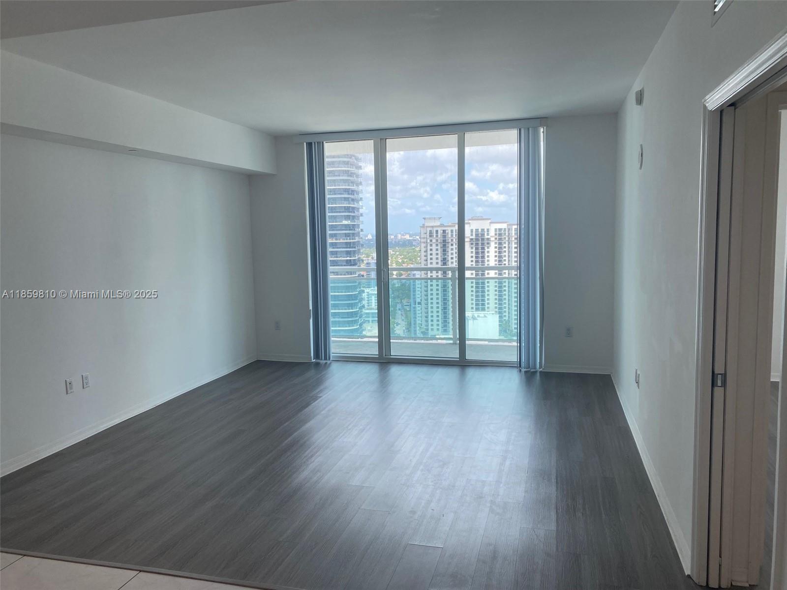 951 Brickell Avenue, Unit 3609 Miami, FL 33131 - Photo 6 of 25 an empty room with wooden floor and sliding door
