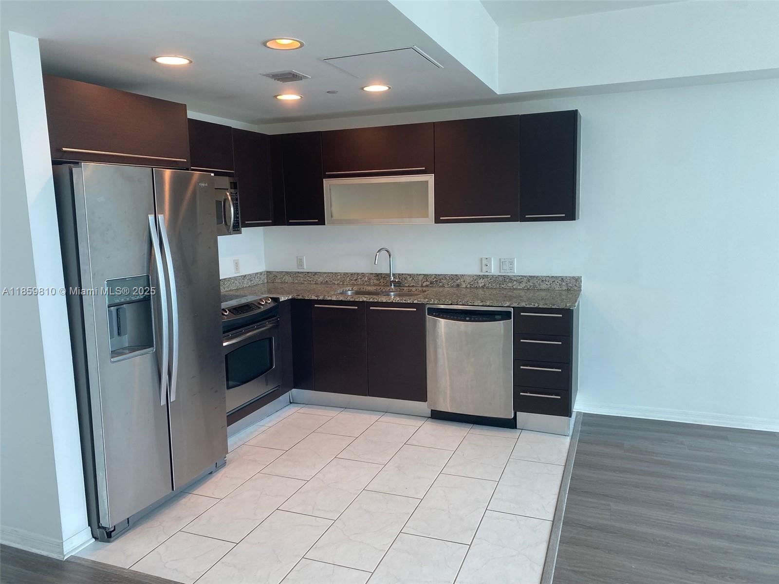 951 Brickell Avenue, Unit 3609 Miami, FL 33131 - Photo 7 of 25 a kitchen with stainless steel appliances granite countertop a stove top oven a sink and a refrigerator