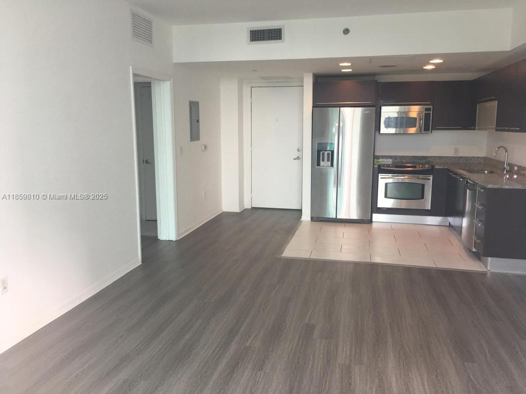 951 Brickell Avenue, Unit 3609 Miami, FL 33131 - Photo 8 of 25 an empty room with wooden floor and a kitchen