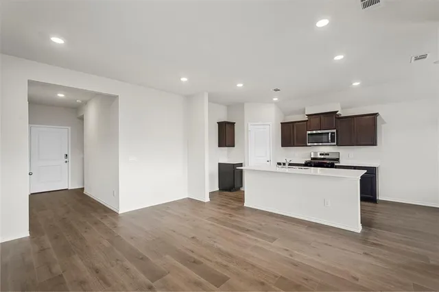 a view of kitchen with microwave stove refrigerator and cabinets