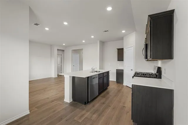 a large kitchen with stainless steel appliances a large counter top a stove a sink and a refrigerator