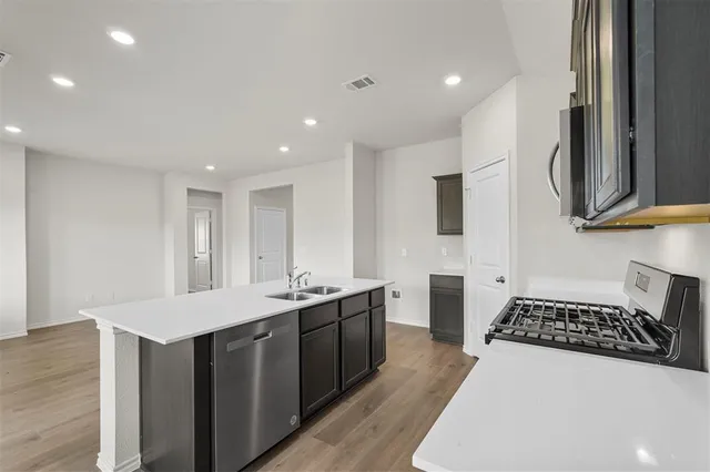a kitchen with stainless steel appliances a stove a sink a refrigerator and cabinets
