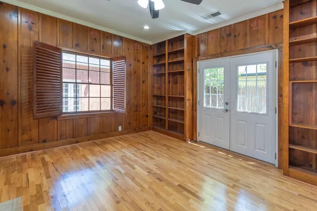 a view of an empty room with a window and wooden floor
