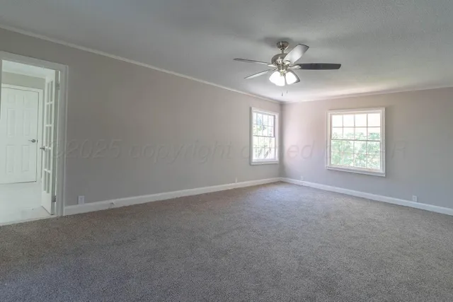 an empty room with windows and fan