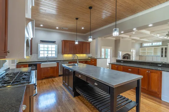 a kitchen with stainless steel appliances granite countertop a sink a stove and a wooden floor
