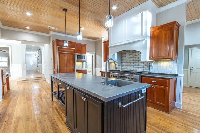 a kitchen with stainless steel appliances granite countertop a sink a stove and a wooden floors