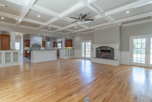 an empty room with wooden floor a fireplace and a kitchen space