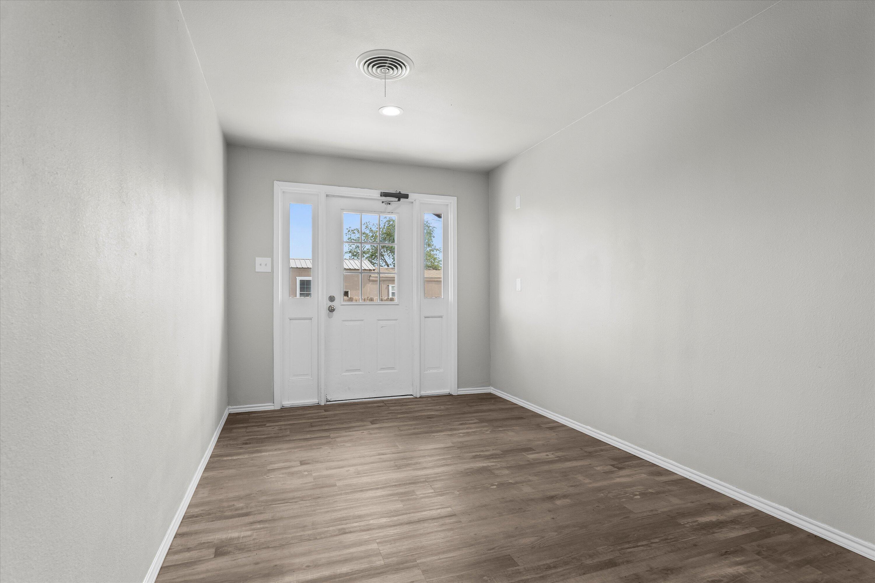 327 Hiracheta Drive New Home, TX 79381 - Photo 24 of 26 an empty room with wooden floor and windows