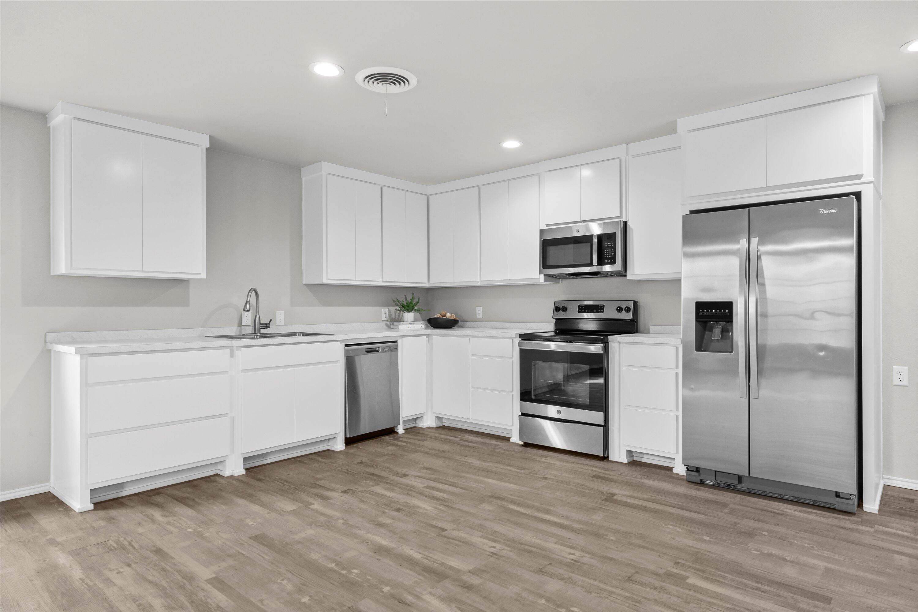 327 Hiracheta Drive New Home, TX 79381 - Photo 6 of 26 a kitchen with a refrigerator stove and white cabinets