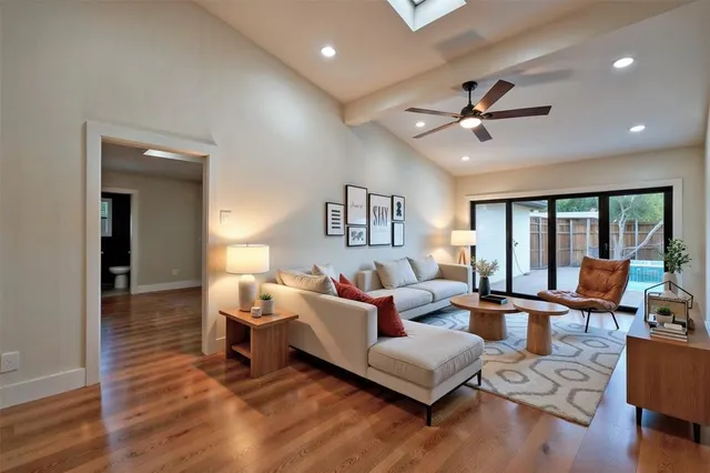 a living room with furniture large window and wooden floor