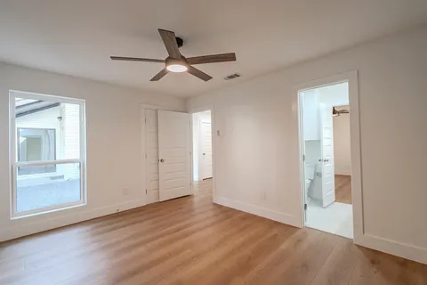 a view of empty room with wooden floor and fan