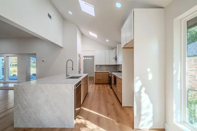 a view of a kitchen with kitchen island a large window a sink and a counter top space