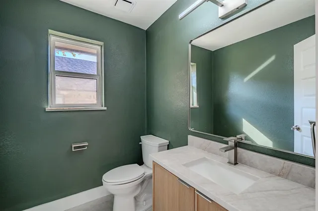 a bathroom with a granite countertop toilet sink and mirror