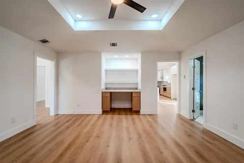 an empty room with wooden floor a ceiling fan and windows