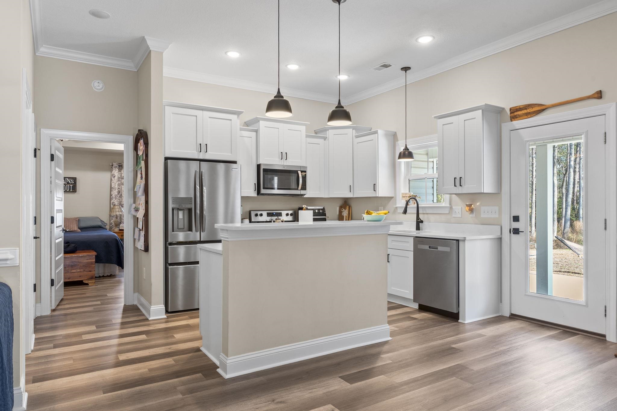 3394 Dusty Road Loris, SC 29569 - Photo 17 of 37 Kitchen featuring a center island, appliances with stainless steel finishes, white cabinets, hanging light fixtures, and light wood-style flooring
