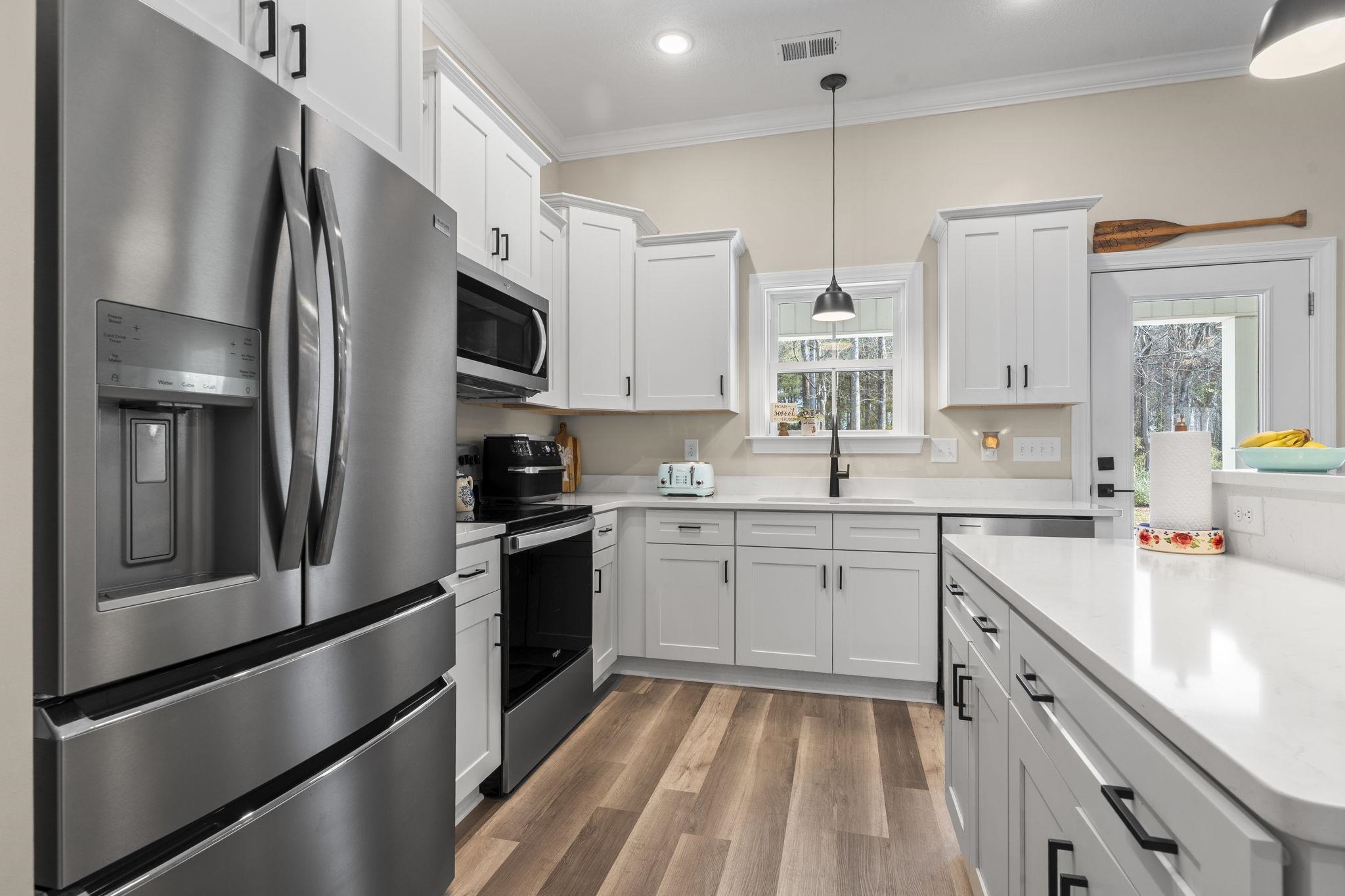 3394 Dusty Road Loris, SC 29569 - Photo 21 of 37 Kitchen featuring appliances with stainless steel finishes, white cabinetry, light wood-style flooring, pendant lighting, and ornamental molding