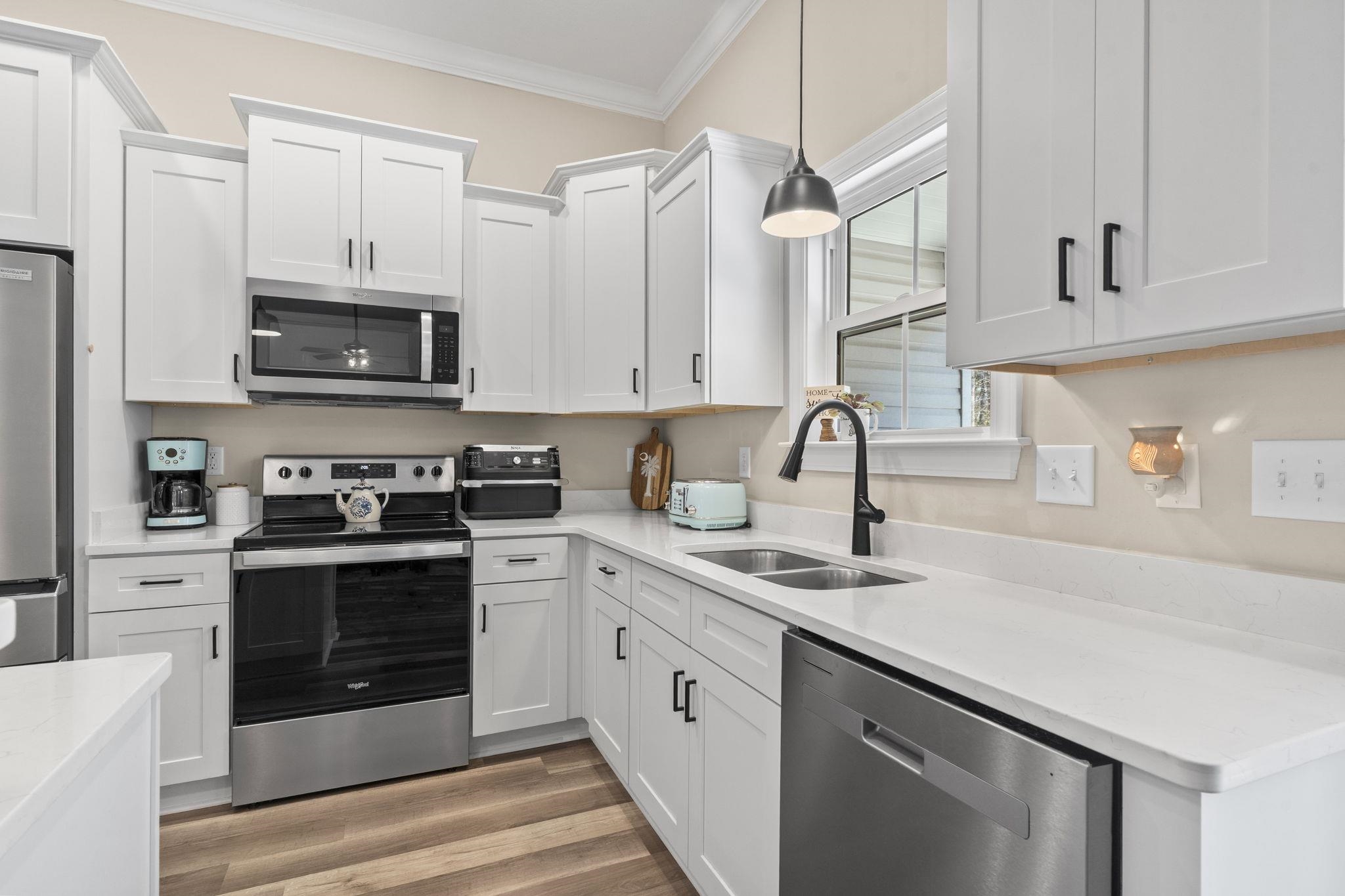 3394 Dusty Road Loris, SC 29569 - Photo 22 of 37 Kitchen with appliances with stainless steel finishes, hanging light fixtures, white cabinets, ornamental molding, and light stone countertops