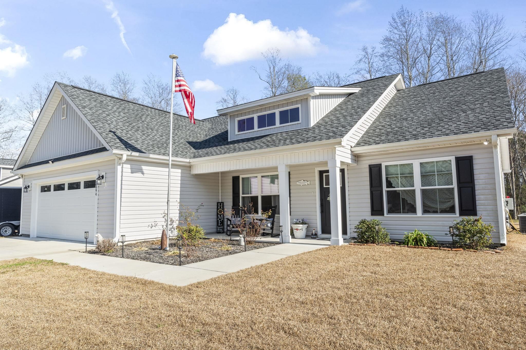 3394 Dusty Road Loris, SC 29569 - Photo 32 of 37 View of front of house with a porch, a shingled roof, a front lawn, and a garage