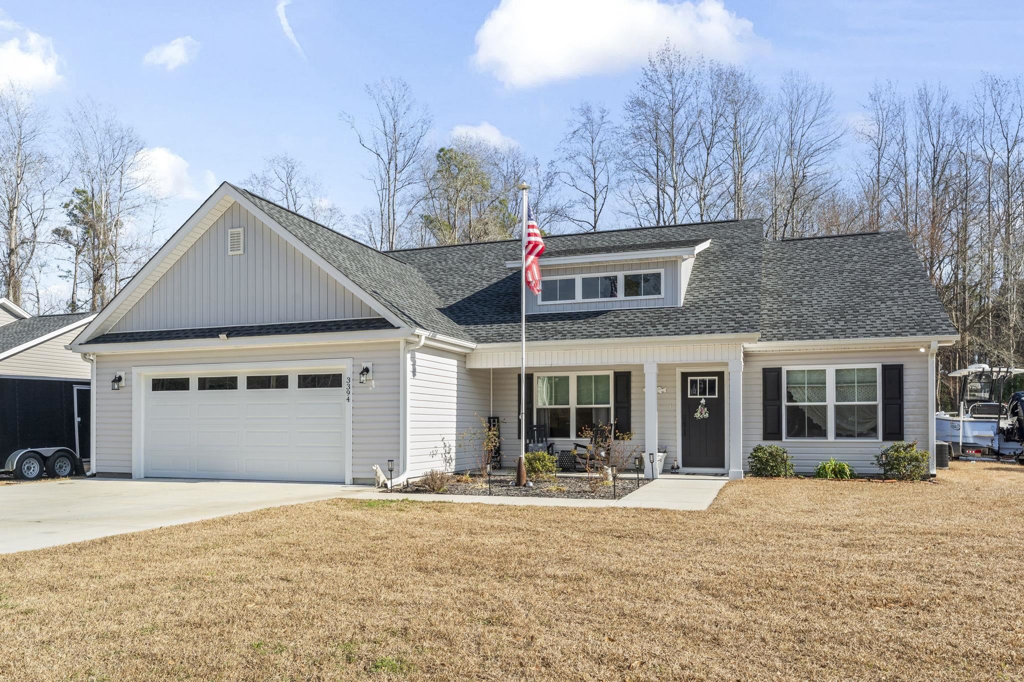 3394 Dusty Road Loris, SC 29569 - Photo 33 of 37 View of front of home featuring a porch, a shingled roof, a front yard, board and batten siding, and concrete driveway