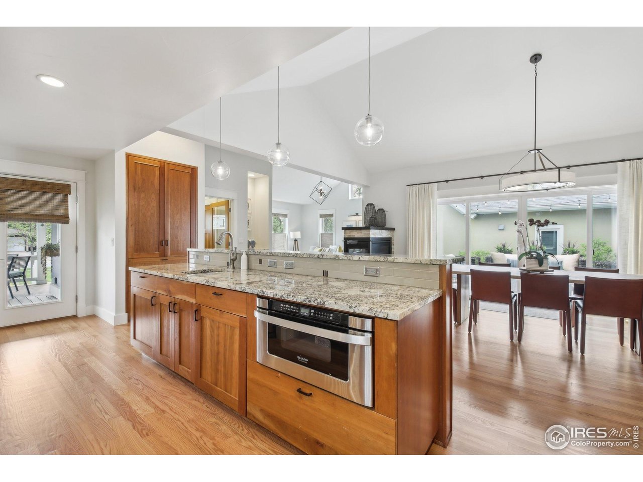 2917 13th Street Boulder, CO 80304 - Photo 10 of 40 a kitchen with stainless steel appliances granite countertop a kitchen island a stove a sink a dining table and chairs with wooden floor