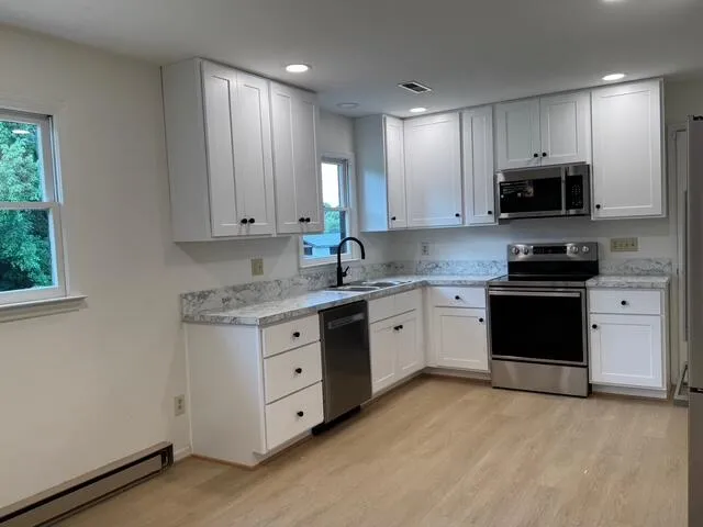 a kitchen with granite countertop white cabinets and stainless steel appliances