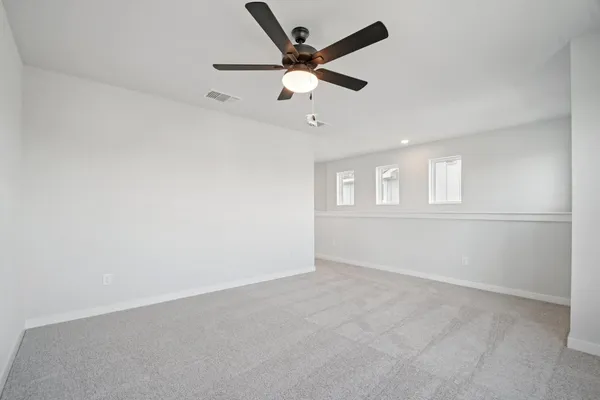 an empty room with wooden floor ceiling fan and windows