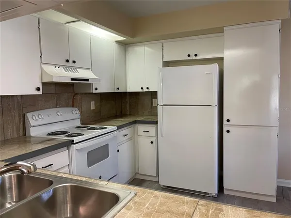 a kitchen with cabinets stainless steel appliances and a refrigerator