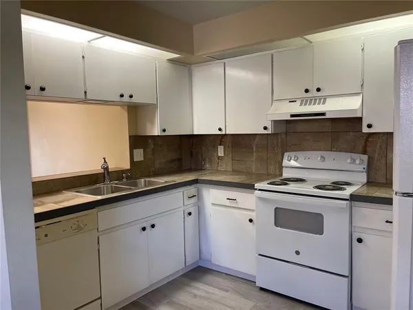 a kitchen with granite countertop white cabinets and white appliances