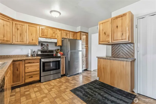 a kitchen with granite countertop a refrigerator stove and sink