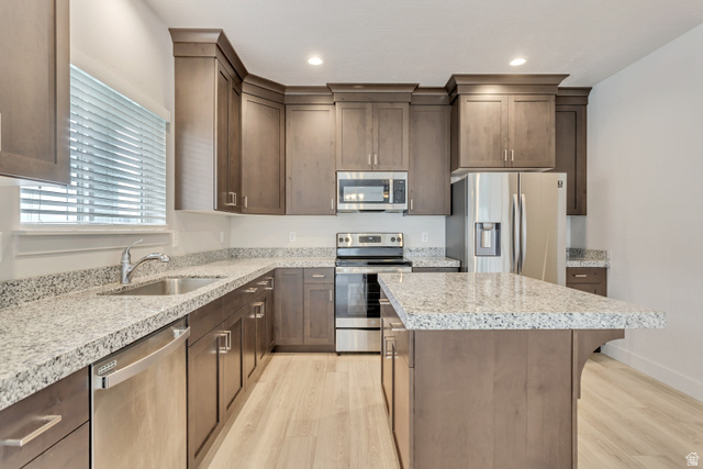 4572 Flower Point Eagle Mountain, UT 84005 - Photo 18 of 62 Modern kitchen featuring wood-finish cabinetry, light-toned countertops, and stainless steel appliances