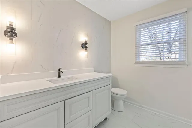a bathroom with a granite countertop toilet sink and mirror