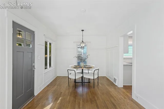 a dining room with wooden floor a chandelier a glass table and chairs