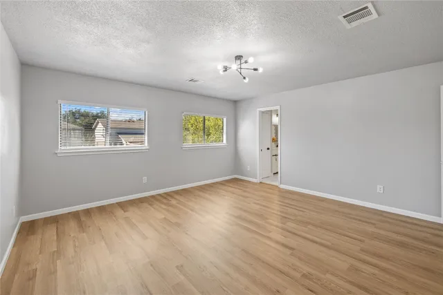 a view of an empty room with a window and wooden floor