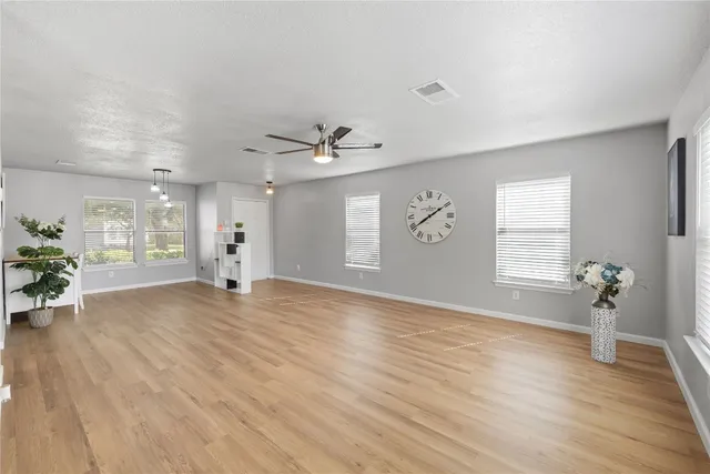 a view of an empty room with a window and wooden floor