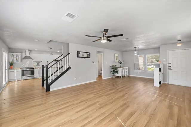 a view of large livingroom with wooden floor and a ceiling fan