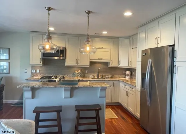 a kitchen with stainless steel appliances granite countertop a stove refrigerator a oven a sink and chairs