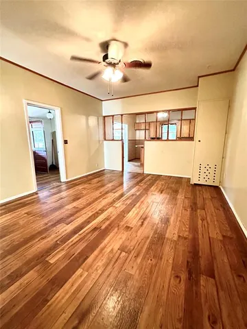 a view of empty room with wooden floor and fan