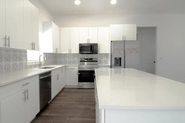 a kitchen with a sink a counter top space stainless steel appliances and cabinets