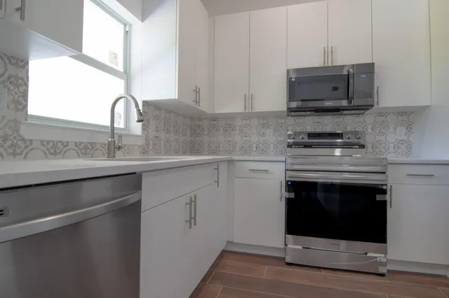 a kitchen with stainless steel appliances granite countertop a stove microwave and sink