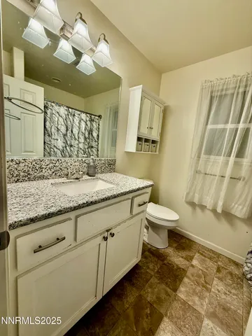 a bathroom with a granite countertop sink a toilet and a mirror