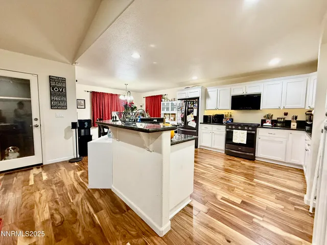 a living room with stainless steel appliances kitchen island granite countertop a refrigerator and a stove top oven
