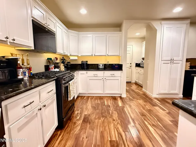 a kitchen with wooden floors and white cabinets