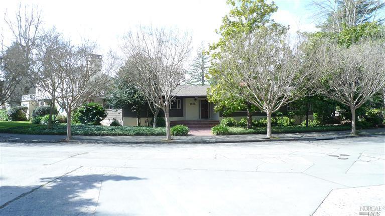 a view of a house with a yard and large trees