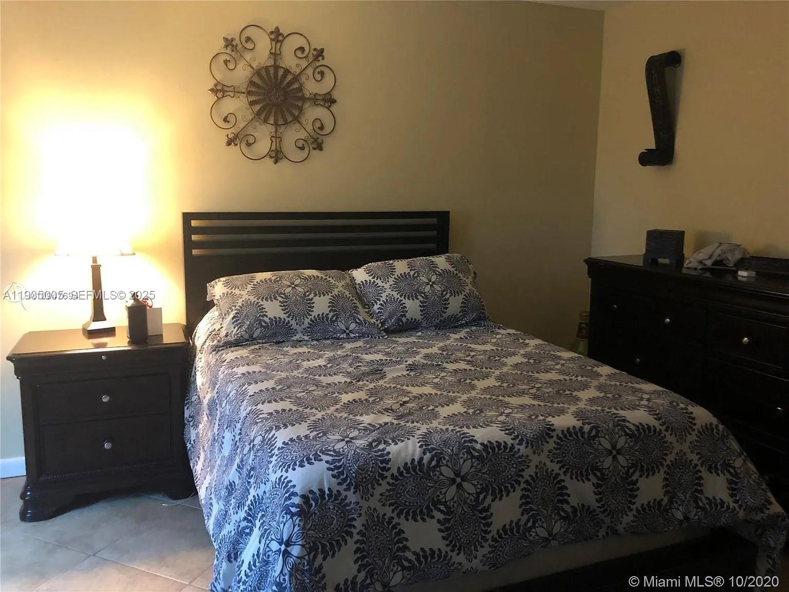9440 Southwest 8th Street, Unit 402 Boca Raton, FL 33428 - Photo 3 of 19 a bed sitting in a bedroom next to a window with a cabinet