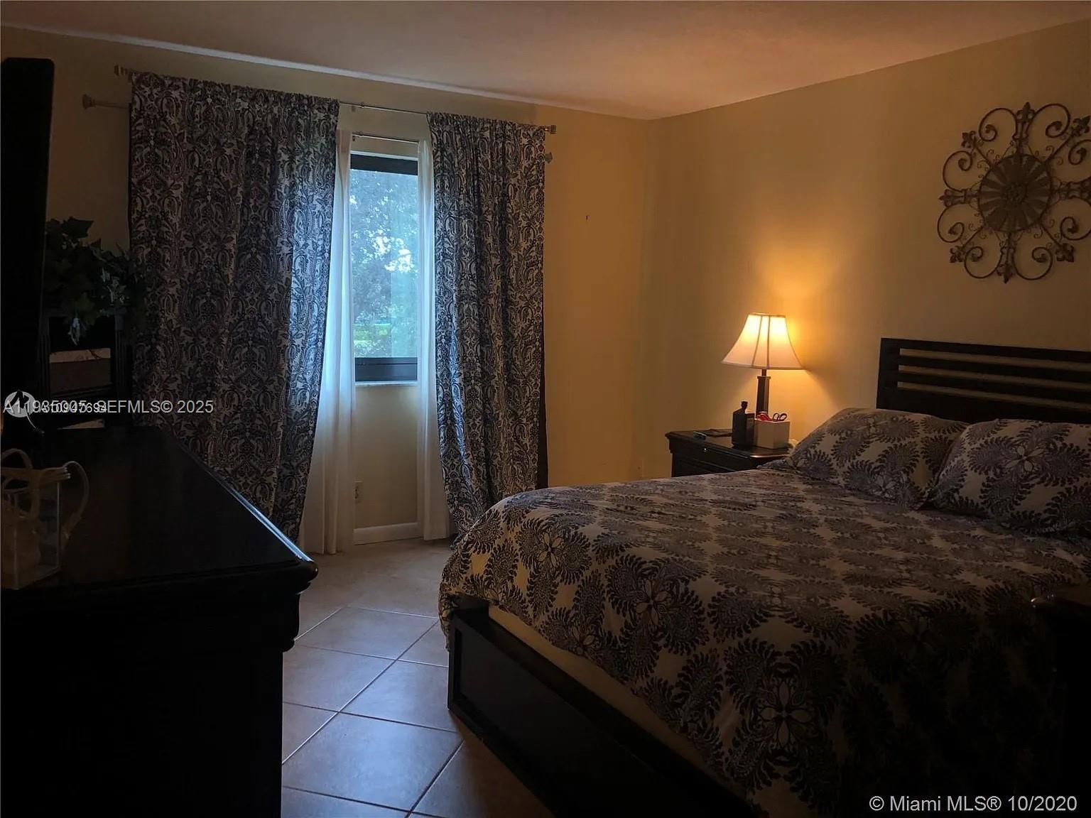 9440 Southwest 8th Street, Unit 402 Boca Raton, FL 33428 - Photo 4 of 19 a bedroom with a bed lamp and a window