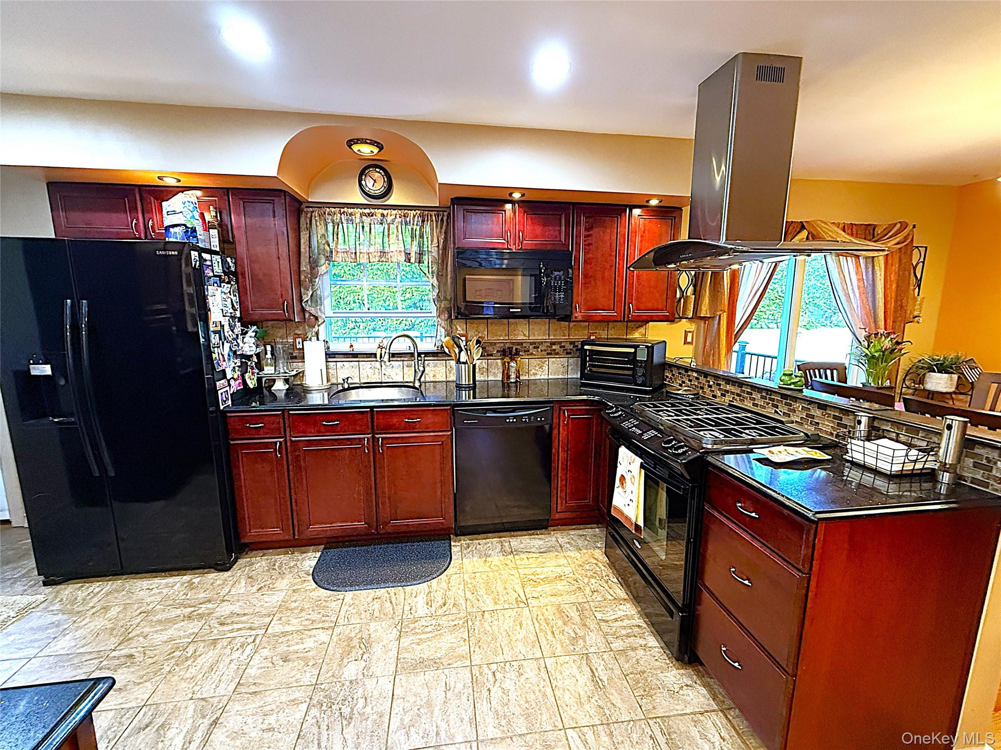 1 Heston Road Shirley, NY 11967 - Photo 13 of 32 Kitchen featuring dark wood-finish cabinetry, black stone countertops, a tile backsplash, and stainless steel range hood