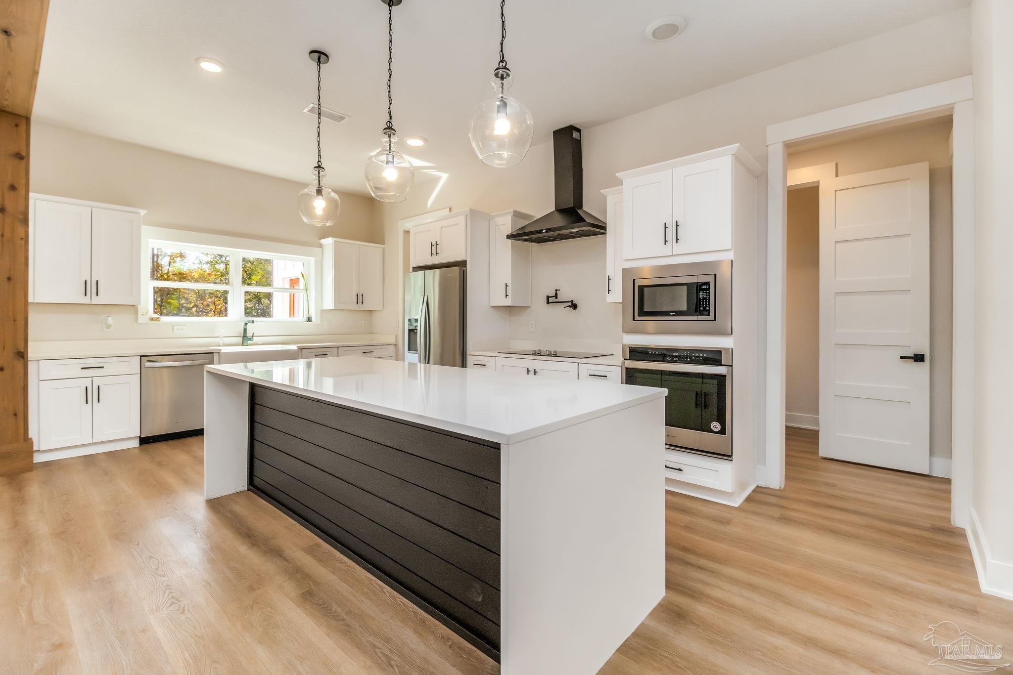 2329 Molino Bridge Road Pace, FL 32571 - Photo 16 of 65 a kitchen with kitchen island a sink stainless steel appliances and wooden floor