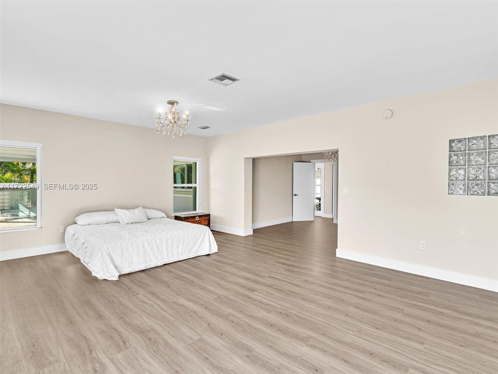 12904 Banyan Road North Miami, FL 33181 - Photo 42 of 87 a spacious bedroom with a large bed chandelier and a window